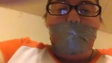 Amateur slavegirl applying a wraparound tape gag for owner